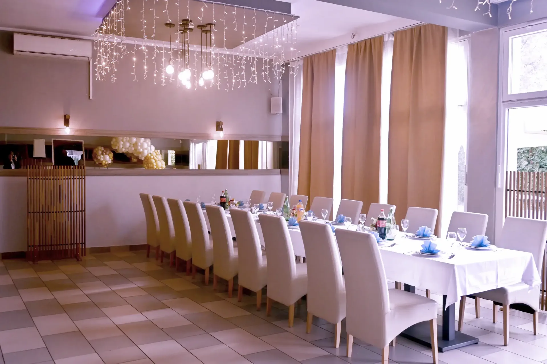 Kod Bosanca velika sala sa redovima posloženih stolaca i stolova priređenih za događanje (bijeli tanjuri, beštek i modre salvete) sa redovima posloženih stolaca i stolova priređenih za događanje (bijeli tanjuri, beštek i modre salvete)