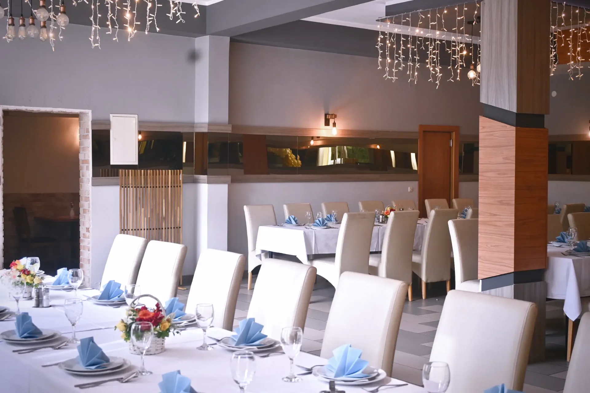 Kod Bosanca velika sala sa redovima posloženih stolaca i stolova priređenih za događanje (bijeli tanjuri, beštek i modre salvete) sa redovima posloženih stolaca i stolova priređenih za događanje (bijeli tanjuri, beštek i modre salvete)
